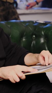 Artist uses sketching technique sitting on sofa in workshop. Creator works on forming painting of mannequin and touches sheet improving skills