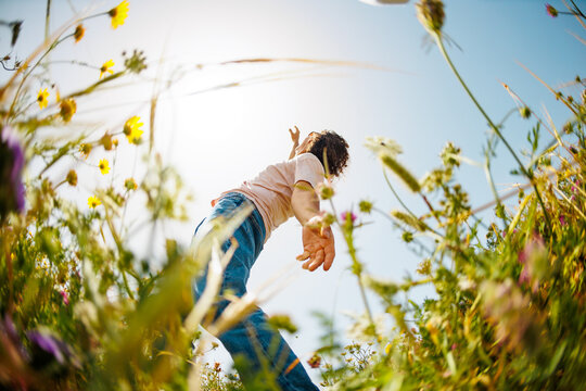 young and cheerful guy dances among the flowers. Handsome man dancing in nature. Summer mood. Happy young guy among blooming flowers, outdoors.