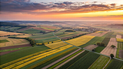 Fototapeta premium Aerial view of farmland landscape at sunrise with fields and crops in countryside scenery for agriculture