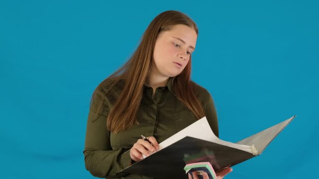 Surprised schoolgirl with pen in hands surprised flips through pages of folder with documents. Woman shocked by amount of homework slow motion