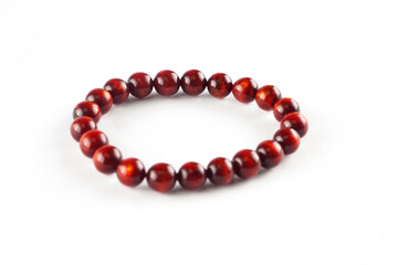 A close-up of a red wooden bead bracelet on a white background. The bracelet is made up of smooth,...