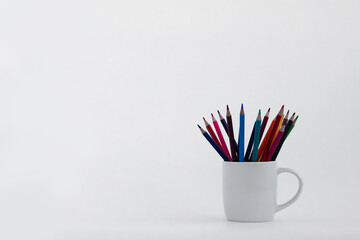 Colorful pencils arranged in white cup on plain background, perfect for creative activities and art...