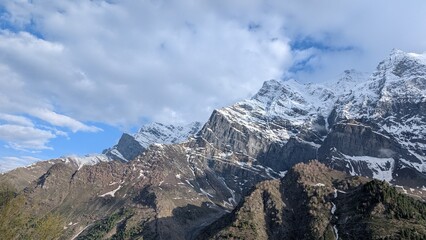 panoramic view of snow filled mountains with texture and clouds in the bright blue sky 