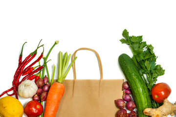 Reusable paper bag with fresh vegetables and fruits. Tomato, cucumber, carrot, celery, lemon, potato, onion, garlic, ginger on white background. Eco-friendly, plastic free and zero waste concept.