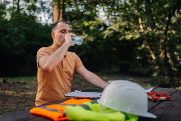 Engineer drinking water after work in park during summer