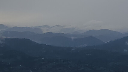 A tranquil scene of layered misty mountains and dense forests, perfect for travel promotions,...