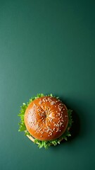 Delicious burger with sesame seed bun on green background top view