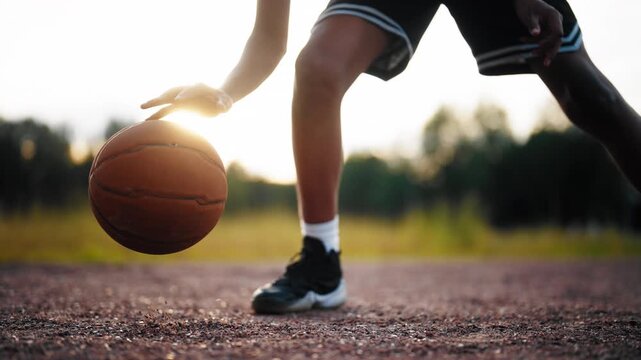 Dribbling and bouncing ball in basketball, closeup view of streetballer workout . Sports activity for teenagers and children, professional sport and hobby, comfortable footwear for sportsmen, details