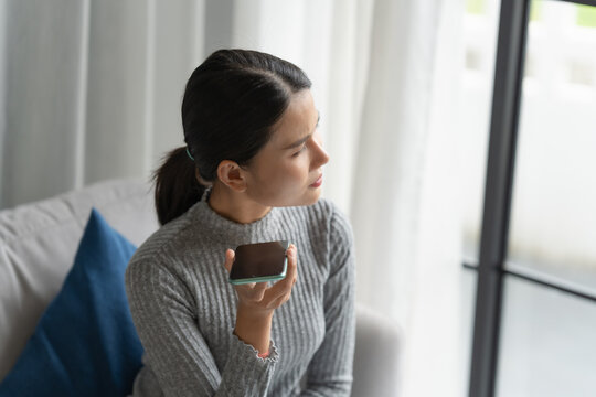 Asian woman using voice assistant on smartphone at home conversation with online assistant Voice chat bot conversational AI Modern Technologies.