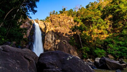 Obraz premium Majestic Waterfall Cascading Down Rocky Cliffside Surrounded by Lush Greenery