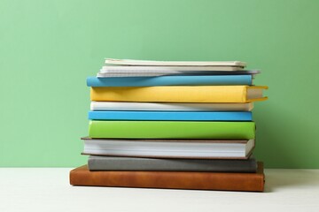 A stack of different books and notebooks on a white desk