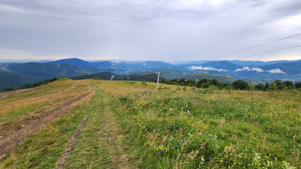 A sweeping view of green hills and distant mountains under a stormy sky, perfect for travel ads,...
