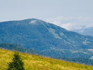 Fototapeta premium A sweeping view of green hills and distant mountains under a stormy sky, perfect for travel ads, nature documentaries, and eco-conscious branding
