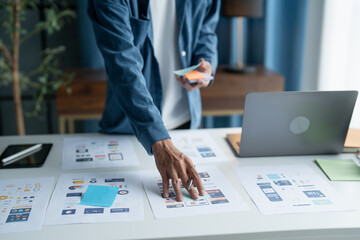 UX UI Designer Planning innovative Mobile App with Paper Wireframe Designs at Workspace.