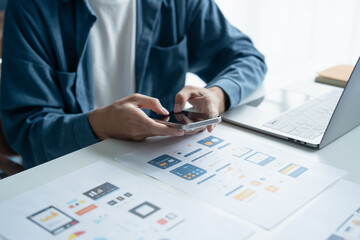 UX UI Designer Planning innovative Mobile App with Paper Wireframe Designs at Workspace.