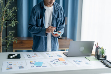 UX UI Designer Planning innovative Mobile App with Paper Wireframe Designs at Workspace.