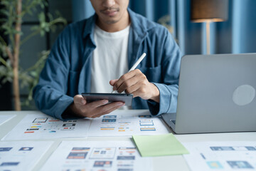 UX UI Designer Planning innovative Mobile App with Paper Wireframe Designs at Workspace.