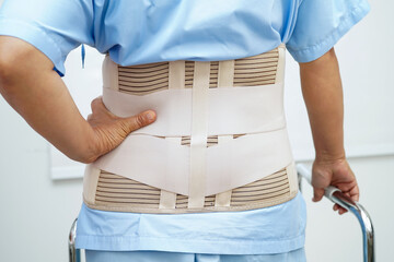 Asian woman wearing lumbar support pain back and use walker in hospital.