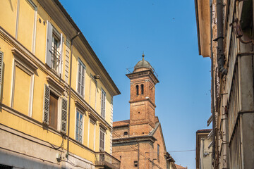 Piacenza, Italy. The bell tower of a historic church is framed by narrow residential buildings on a...