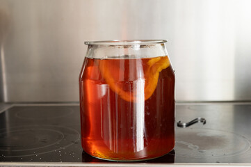 Homemade kombucha brew in glass jar with scoby on kitchen counter