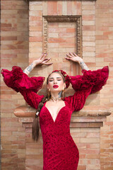 A beautiful woman dancing flamenco rests her hands on the wall above her head and makes facial...
