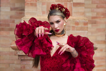 A beautiful woman dancing flamenco in a square in Seville, Spain. She is wearing a red dress with...