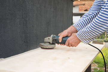 Caucasian male adult using an electric sander for woodwork on outdoor project