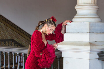 A beautiful woman dancing flamenco leaning against a white column in a square in Seville, Spain....