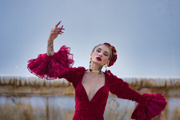 A beautiful woman dancing flamenco in a square in Seville, Spain. She is wearing a red dress with...