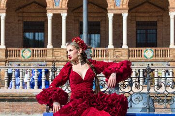 A beautiful woman dancing flamenco sitting on a tiled bench in a square in Seville, Spain. She is...
