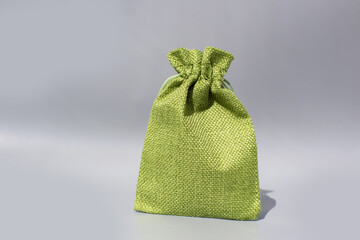 Green fabric gift bag with drawstring on gray background