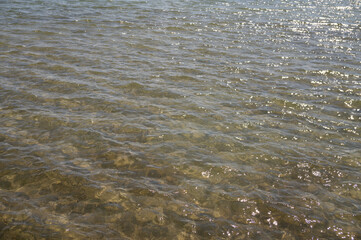 Clear coastal water with sunlight reflections on gentle waves