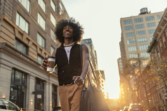 Laughing man walking with coffee in city light - Powered by Adobe
