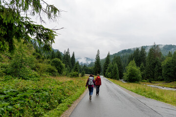  Friends Hiking on a Road Through the Mountains