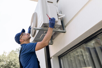 Repairman fixing AC outdoor unit.