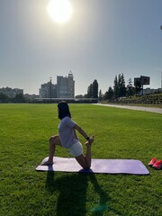 Fototapeta premium Woman Stretching on Yoga Mat Outdoors in Morning Sunlight
