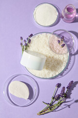 Fresh lavender stems and bath salts in glass bowls arranged on a soft purple background, ideal for advertising organic cosmetic or aromatherapy brands.