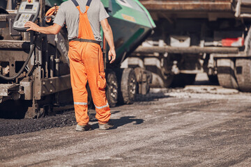 Construction worker working on a new asphalt layer on a public street.