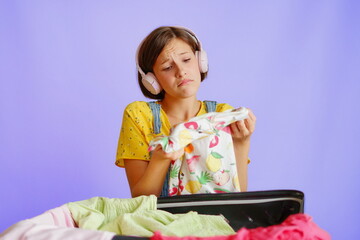 Sad girl in headphones holding t-shirt on white background for shopping campaigns