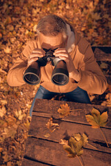 Amateur birdwatcher observing birds and other animals in nature with binoculars.