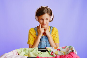 Thoughtful girl in headphones smiling by clothes on white background for shopping campaigns