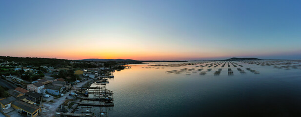 Panoramic view of a sunrise over the Thau lagoon and the oyster farms and their tables.