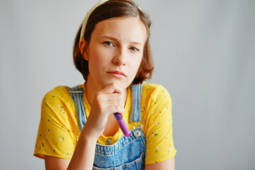 Doubtful young woman eyeing pen on white background for emotional campaigns