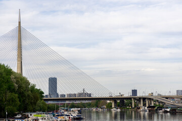 Scenic view of a Bridge with boats docked on the riverbank and a modern skyline in the background.