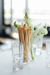 Elegant Table Setting with Breadsticks in Glass and White Flowers