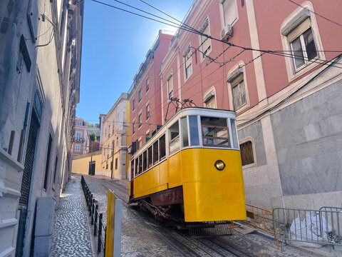 Iconic yellow funicular tram climbing a steep cobblestone street surrounded by colorful buildings