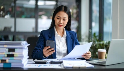 A person flipping through documents on a desk and checking their smartphone