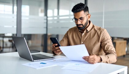 Fototapeta premium A person flipping through documents on a desk and checking their smartphone
