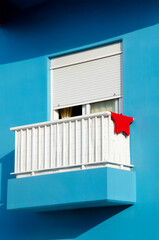 White balcony with hanging red clothing at light blue building wall, perfect aesthetic for reels,...