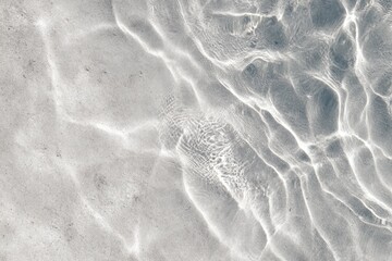Abstract water surface texture, light reflecting on gray-white sand